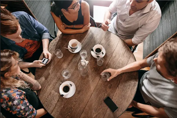 A diverse group of people in a coffee shop, representing demographics and collaboration, illustrating statistics in network marketing.